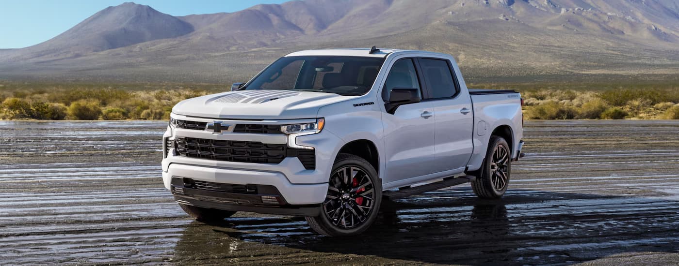 White 2026 Chevy Silverado 1500 parked off-road on a muddy path.