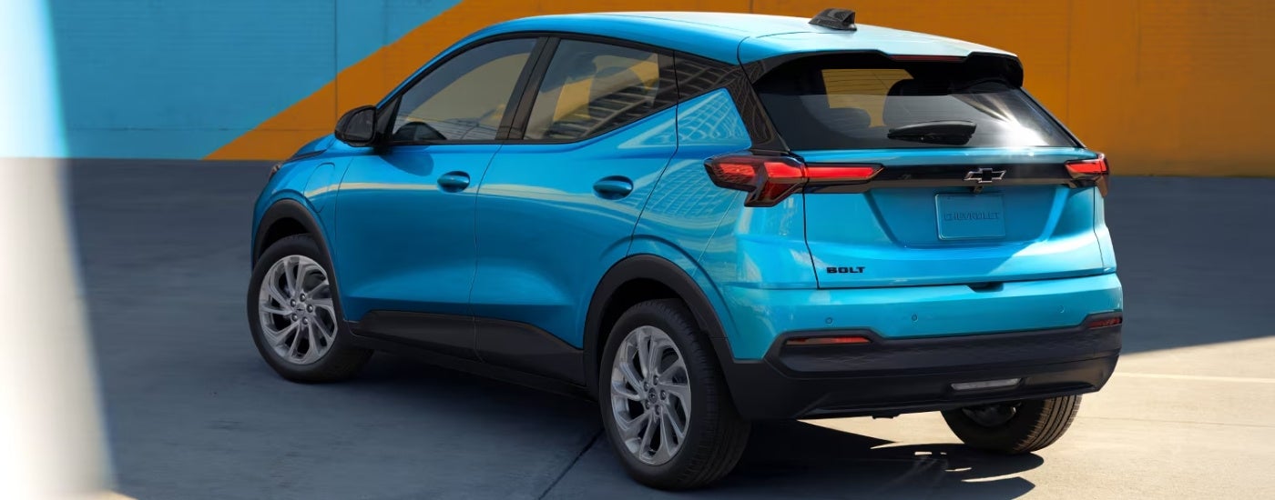 Rear of a blue 2027 Chevy Bolt LT parked near a wall.