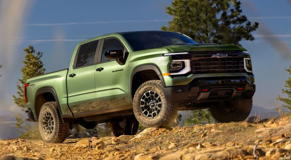 Green 2027 Chevy Silverado 1500 driving on a off-road trail.