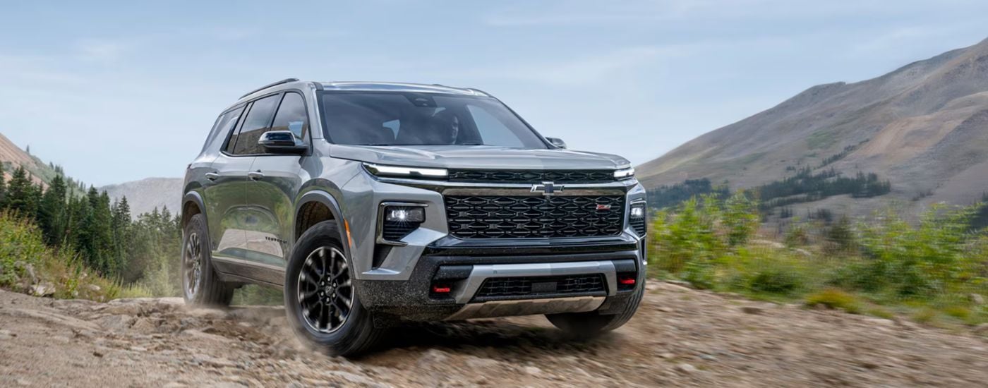 A gray 2026 Chevy Traverse driving on a rocky mountain trail.