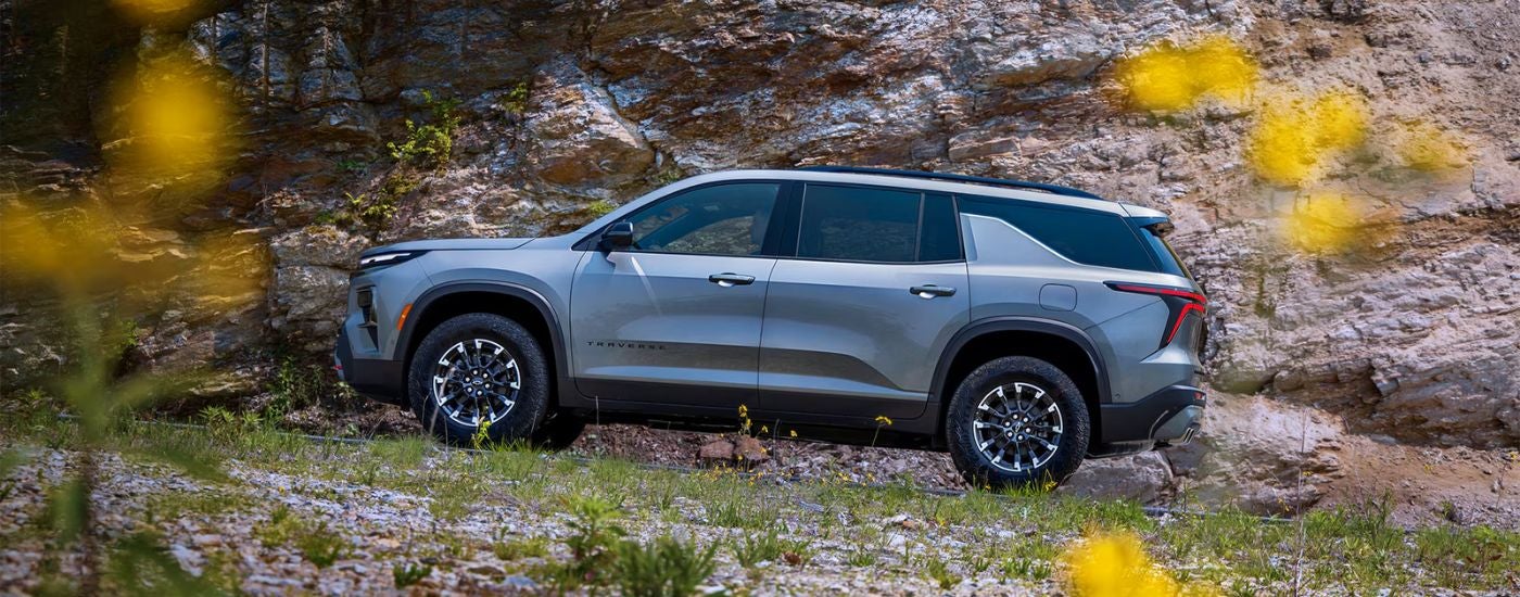 A gray 2026 Chevy Traverse shown driving a rocky dirt road.