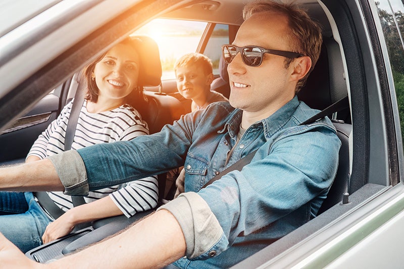 Family driving car with happy father at the wheel